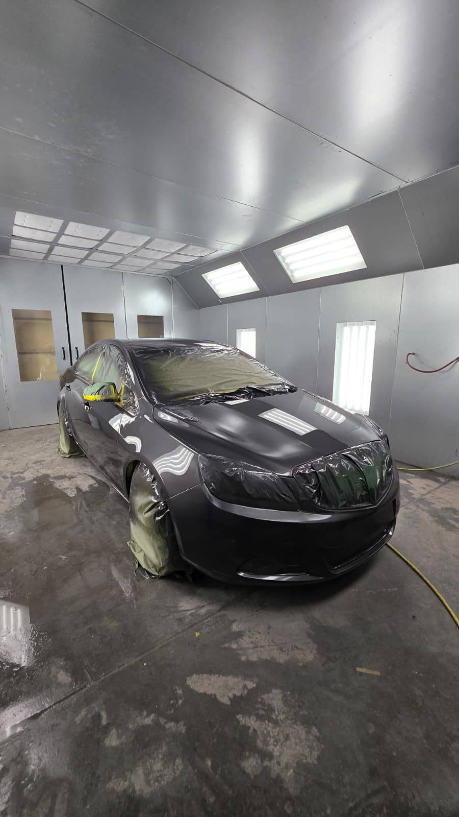 Dark charcoal car masked in paint booth — CarTech